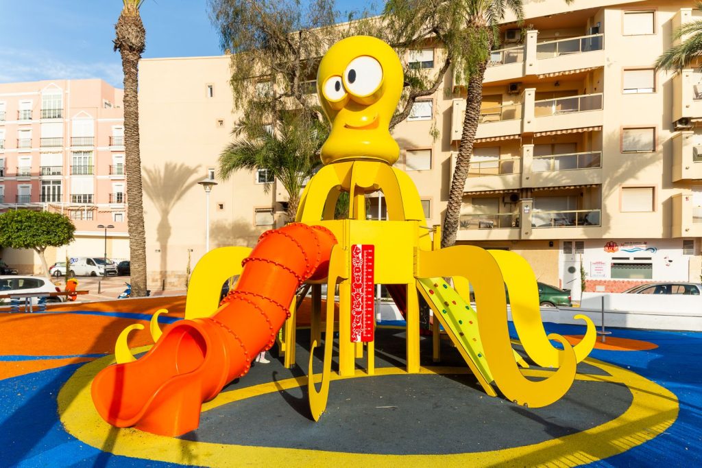 Estructura infantil con faro rojo y puente colgante.